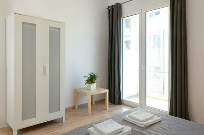 a white bedroom with a mirror and a window at Rhodes Central Apartment in Rhodes Town