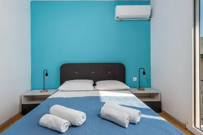 a bed with two pillows on it with a blue wall at Rhodes Central Apartment in Rhodes Town