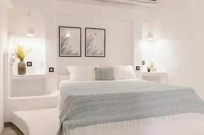 a white bedroom with a bed and two pictures on the wall at Pristine Seaview Villa , with 5-Star Resort Access in Faliraki