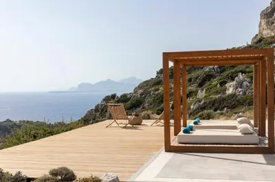 a mirror on a deck with a bed and the ocean at Pristine Seaview Villa , with 5-Star Resort Access in Faliraki