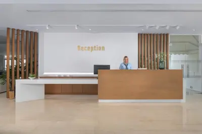 a person standing behind a reception desk in an office at Niriides Hotel in Kolimbia