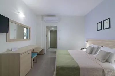 a bedroom with a bed and a desk and a mirror at Niriides Hotel in Kolimbia