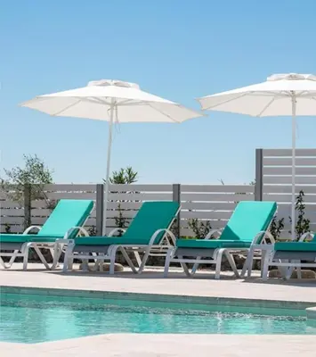 a group of chairs and umbrellas next to a pool at La Residenzia in Kalithies