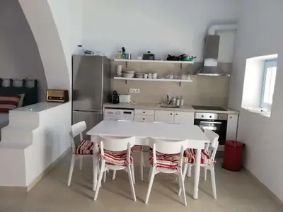 a white kitchen with a white table and chairs at Jasmine Suites Poolhouse Rhodos in Koskinou