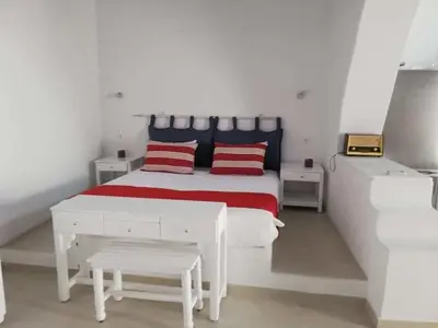 a white bedroom with a white bed with red pillows at Jasmine Suites Poolhouse Rhodos in Koskinou