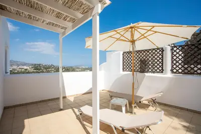a balcony with a table and chairs and an umbrella at Afandou Sea View in Afantou
