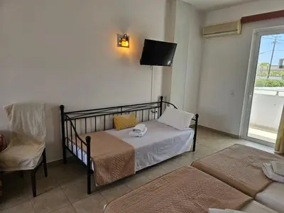a bedroom with a bed and a chair and a tv at Apollonio Rooms Faliraki Rhodes in Faliraki