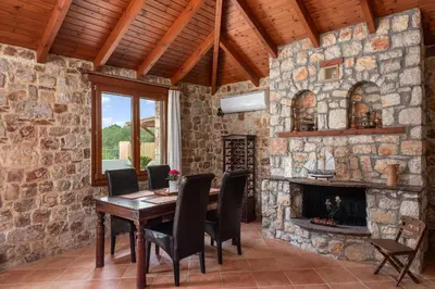 a dining room with a table and a fireplace at Filerolia Stone House in Pastida