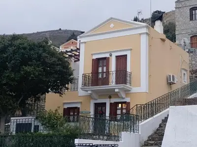 a yellow house with a balcony on the side of it at Constantia in Symi