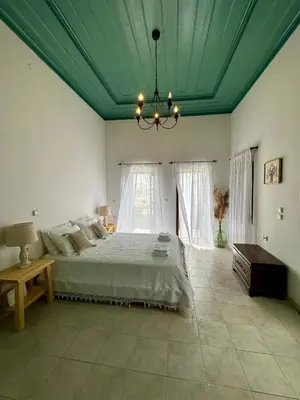 a bedroom with a bed with a green ceiling at Constantia in Symi