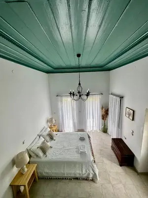 a bedroom with a large bed with a blue ceiling at Constantia in Symi