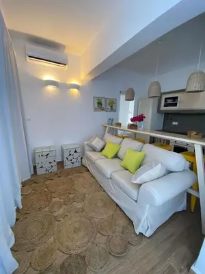 a living room with a white couch with green pillows at Kouros Home & Suites in Faliraki