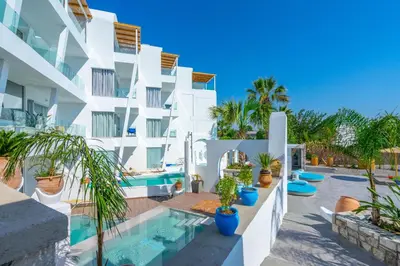 a white apartment building with a swimming pool and plants at Kouros Home & Suites in Faliraki