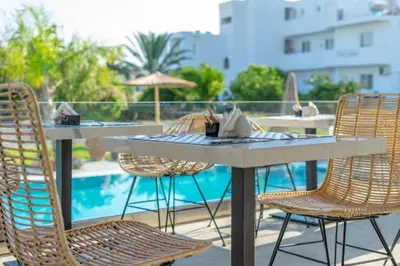 a table and chairs sitting on a patio with a pool at Kouros Home & Suites in Faliraki