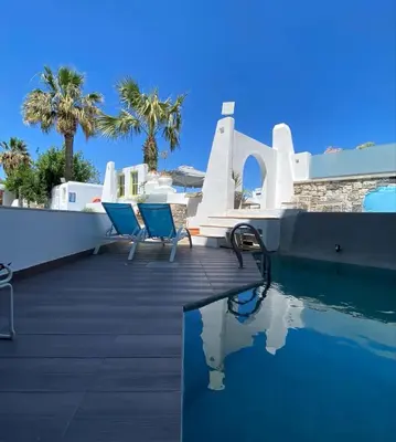 a swimming pool with two blue chairs next to a house at Kouros Home & Suites in Faliraki