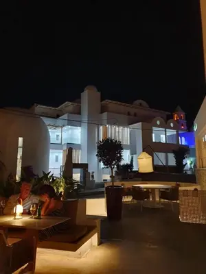 a view of a building at night with tables and chairs at Kouros Home & Suites in Faliraki
