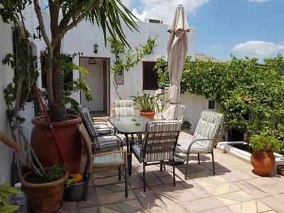 a patio with a table and chairs and an umbrella at Soultana studios in Líndos