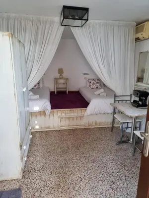a bedroom with two beds with curtains and a table at Soultana studios in Líndos