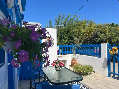 a patio with a table and flowers on a blue fence at My sweet Greek dream - Traditional home in Soroni