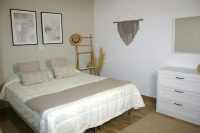 a white bedroom with a bed and a dresser at Kuspa House Soroni in Soroni