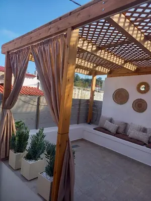 a patio with a wooden pergola with potted plants at Kuspa House Soroni in Soroni