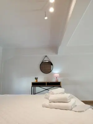 a room with a bed with white sheets and a table at KAZERMA ΗΟΜΕ in Rhodes Town
