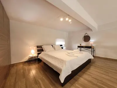 a bedroom with a large bed and a wooden floor at KAZERMA ΗΟΜΕ in Rhodes Town