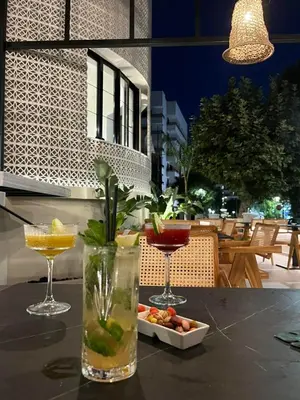 a table with two cocktails and a plate of food at Naillac Boutique Hotel in Rhodes Town