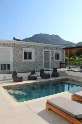 a swimming pool with chaise lounge chairs next to a house at Casa Nikolou Stegna in Archangelos
