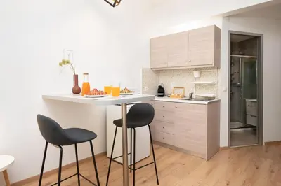 a kitchen with a white counter and two stools at Gravity Downtown Scandi Studio in Rhodes Town