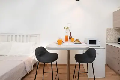 a white table with two black chairs next to a bed at Gravity Downtown Scandi Studio in Rhodes Town