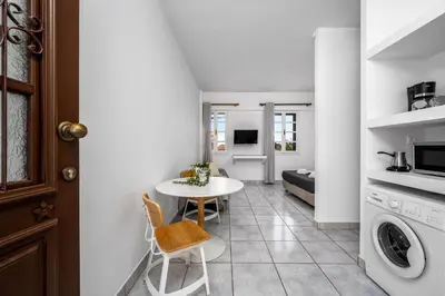 a small kitchen and living room with a table and chairs at Cleomenes Old Town Studios in Rhodes Town