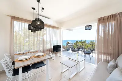 a living room with a dining table and a view of the ocean at ANASTASIOS HOUSE STEGNA - UP FLOOR in Archangelos