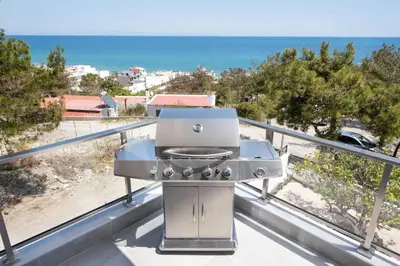 a grill on a balcony with a view of the ocean at ANASTASIOS HOUSE STEGNA - UP FLOOR in Archangelos