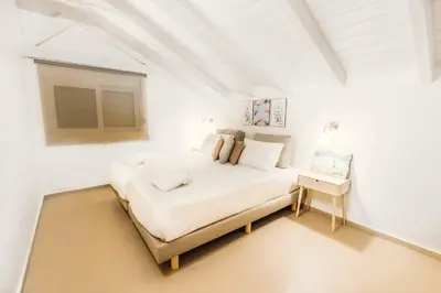 a white bedroom with a large bed and a table at Ammos Beach House in Kiotari