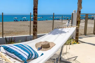 a hammock with a straw hat on it next to the beach at Ammos Beach House in Kiotari