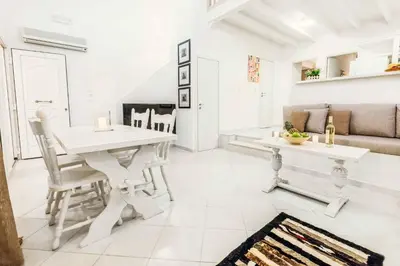 a white living room with a white table and chairs at Ammos Beach House in Kiotari