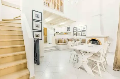a white dining room with a table and a fireplace at Ammos Beach House in Kiotari