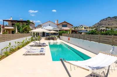 a swimming pool with two hammocks on a house at Ammos Beach House in Kiotari