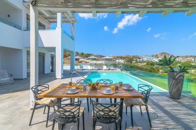 a dining table and chairs on a patio with a pool at Villa Krini Delight in vlicha