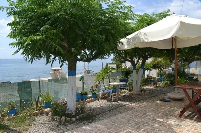 a patio with a table and a white umbrella at GALINI STEGNA BEACH in Archangelos
