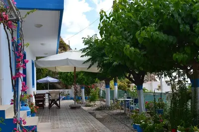 a patio with an umbrella and tables and chairs at GALINI STEGNA BEACH in Archangelos