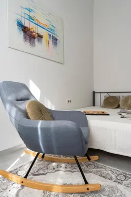 a blue chair in a living room next to a bed at Beautiful Neoclassical House in Rhodes town in Rhodes Town