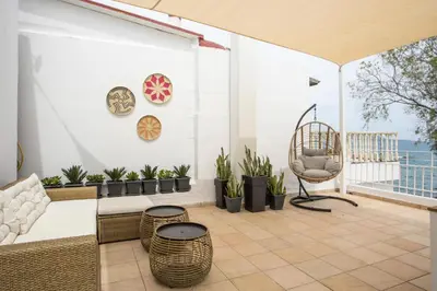 a patio with plants and a chair on a balcony at Salty Beach Front House Faliraki in Faliraki