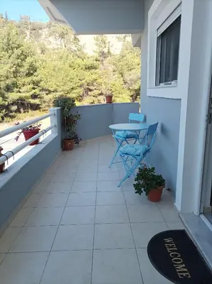 a balcony with a blue table and a window at Home Away From Home in Ixia