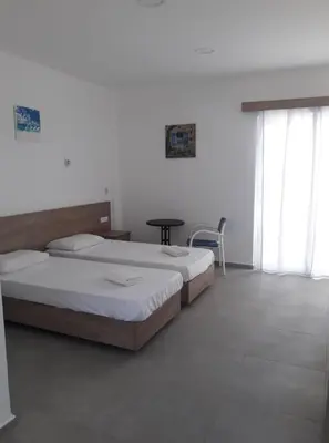 a bedroom with two beds and a table and windows at Pefki Irish Seaview in Pefki Rhodes