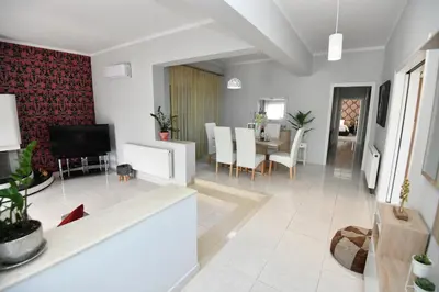 a living room with a television and a dining room at Eva's Garden House in Ialyssos