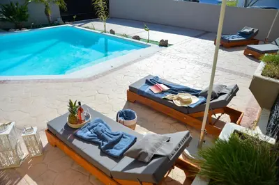 a swimming pool with lounge chairs and a table at Eva's Garden House in Ialyssos