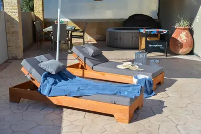 two beds sitting on a patio with a table at Eva's Garden House in Ialyssos