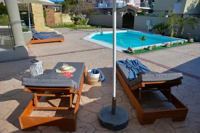 two beds and an umbrella next to a swimming pool at Eva's Garden House in Ialyssos